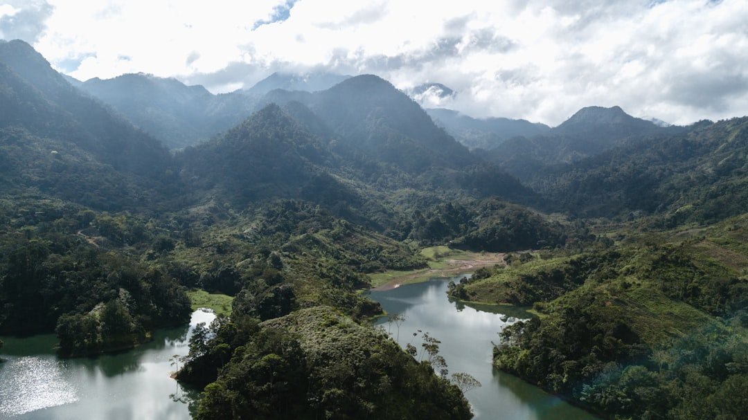 Photo by Esteban Benites green mountains and river under white clouds during daytime
